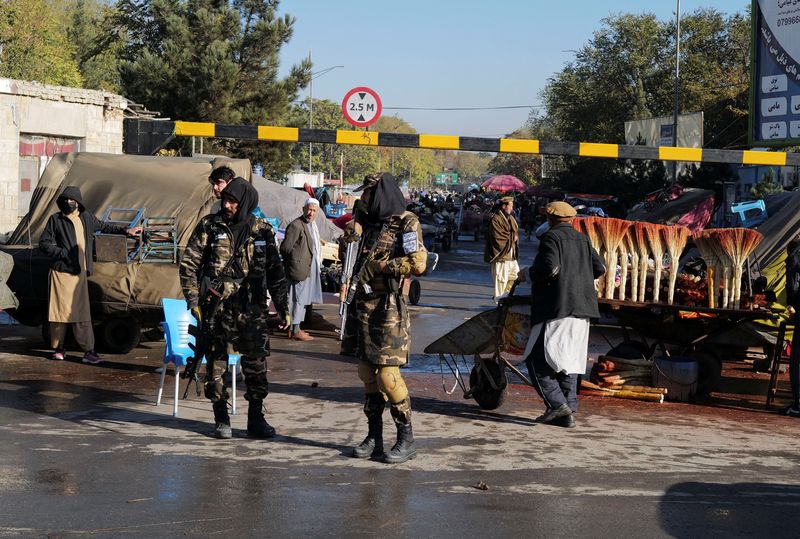 Taliban fighters stand as they hold a checkpoint in Kabul