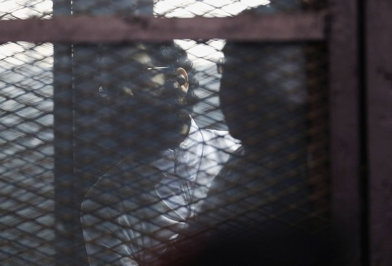 Activist Alaa Abdel Fattah stands behind bars before his verdict