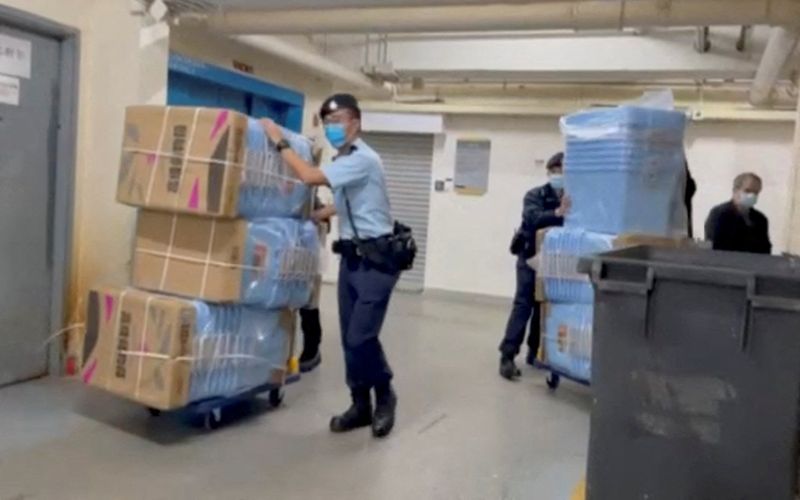 Police officers push boxes to collect evidence during their raid