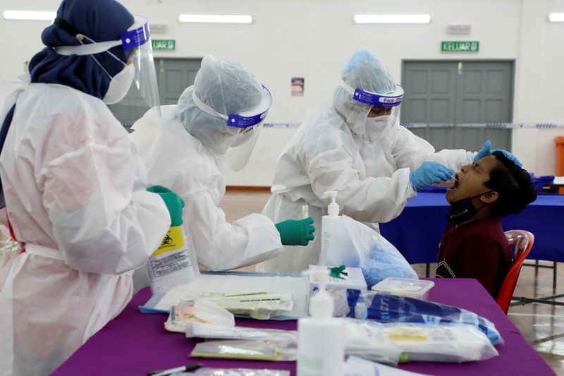 Medical workers wearing personal protective equipment (PPE) collect a swab