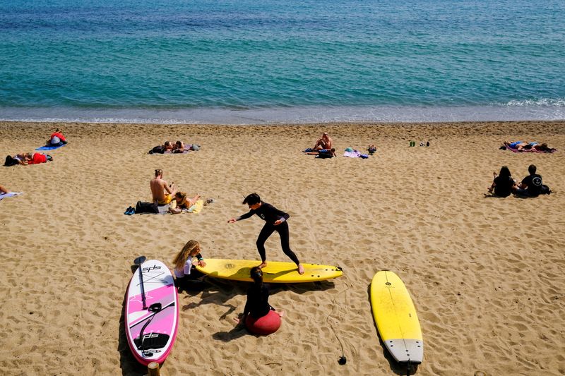 FILE PHOTO: A person teaches surfing to children at Barceloneta