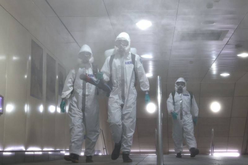 Soldiers in protective suits disinfect a metro station