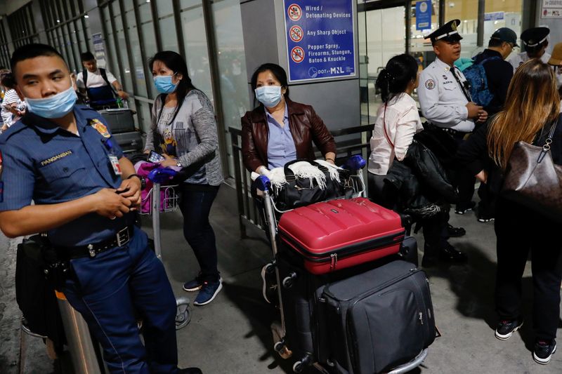 Overseas Filipino Workers (OFW) wearing protective masks standby outside the