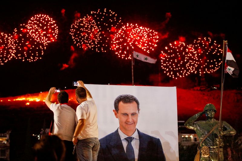 FILE PHOTO: Supporters of Syria’s President Bashar al-Assad celebrate after