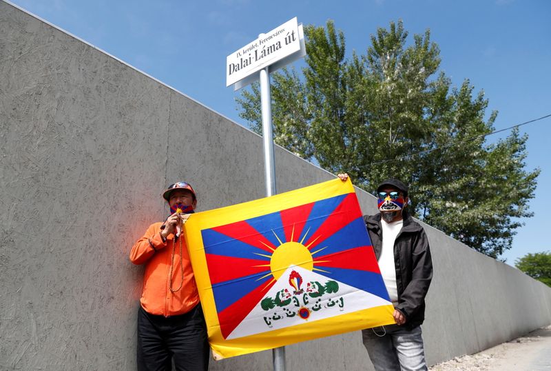 Activists hold a Tibetan flag next to a sign in