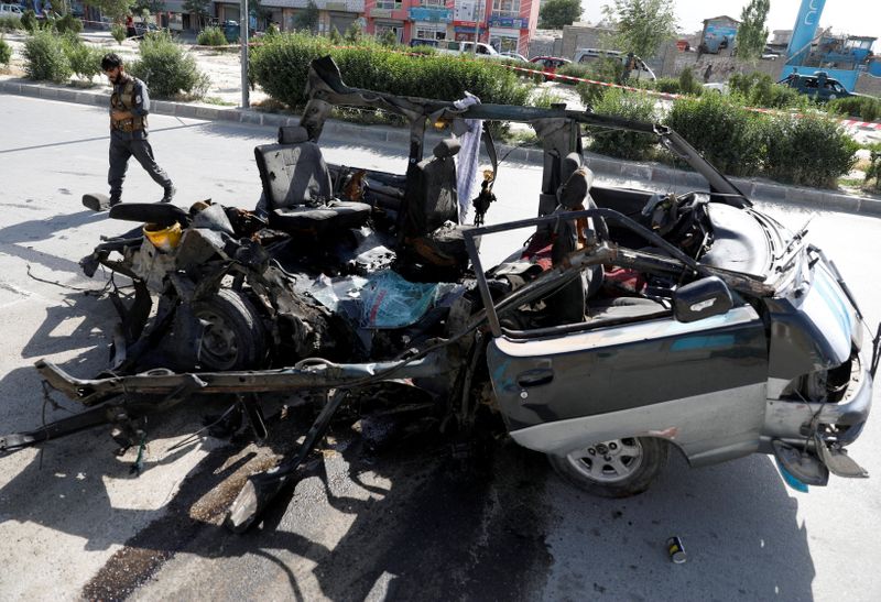 Afghan police officer inspects a damaged van after a blast