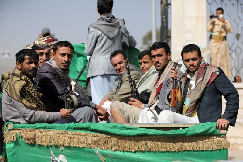 FILE PHOTO: Armed Houthi followers ride on the back of
