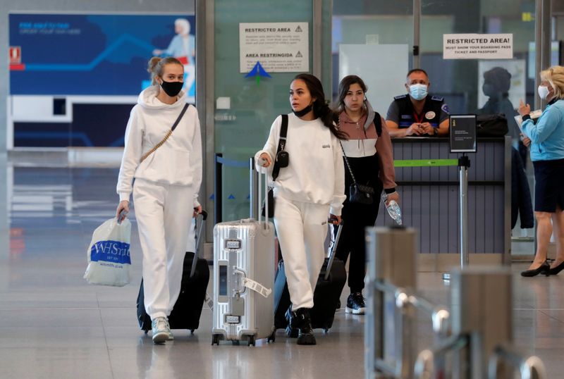 Tourists walk with their luggage as they arrive at Malaga-Costa