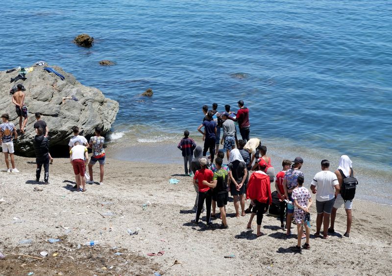 FILE PHOTO: Migrants stand on the beach in Fnideq, close