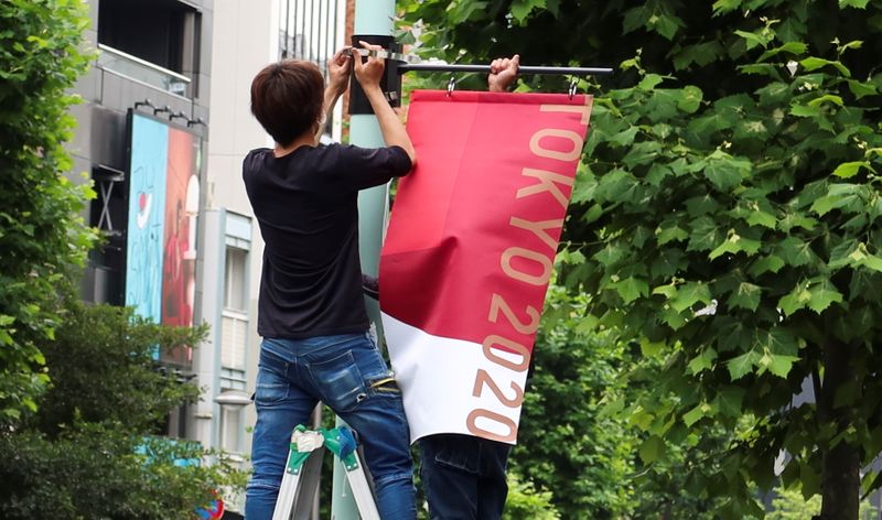 Workers attach the Tokyo 2020 Olympic Games banner on a