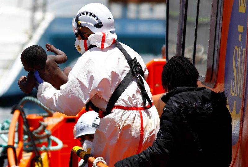 Rescuers help a migrant child to disembark from a Spanish
