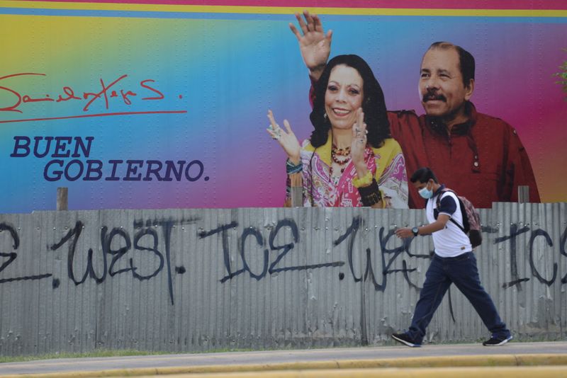 Man walks by billboard showing Nicaragua’s President Ortega and Vice
