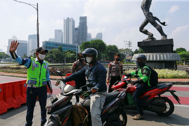 Officials stop motorbikes while enforcing large-scale social restrictions to prevent