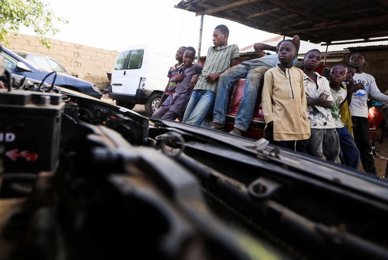 Boys stand at a mechanic workshop in Kaduna