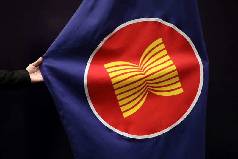 A worker adjusts an ASEAN flag at a meeting hall