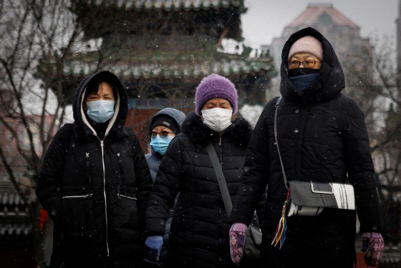 FILE PHOTO: People wear face masks as they walk on