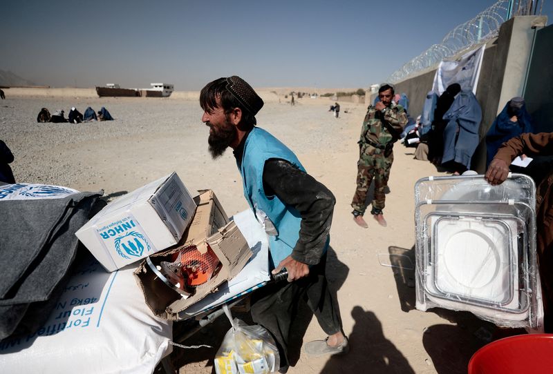 FILE PHOTO: UNHCR worker pushes a wheelbarrow loaded with aid