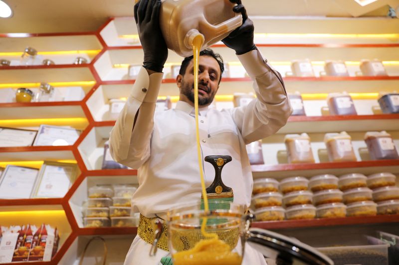 Vendor Helmi al-Marhebi pours honey into a glass bowl at
