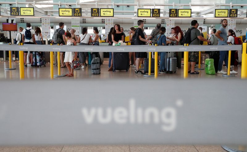 People queue in front of Vueling customer support desk at