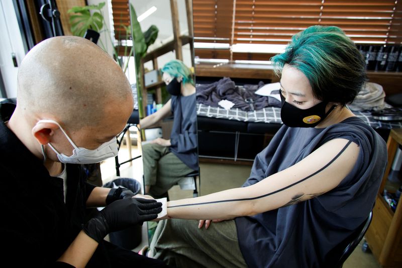 Tattooist Kim Do-yoon attends to a customer in his tattoo