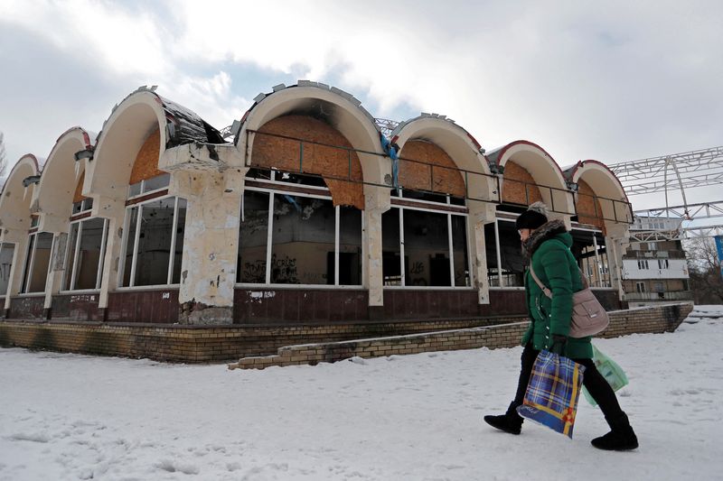 FILE PHOTO: A woman walks past a damaged shop in