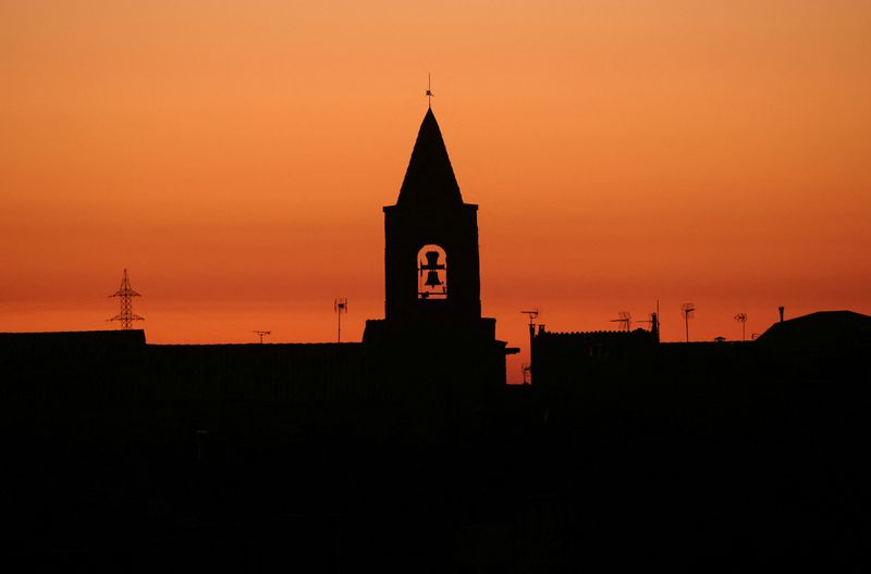 The bell tower of a church is seen during sunset