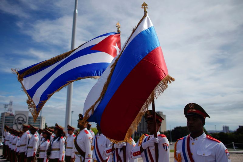 Honor guards hold a Russian and a Cuban flag during