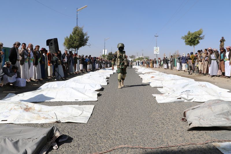 FILE PHOTO: Houthi policeman walks past bodies of victims of