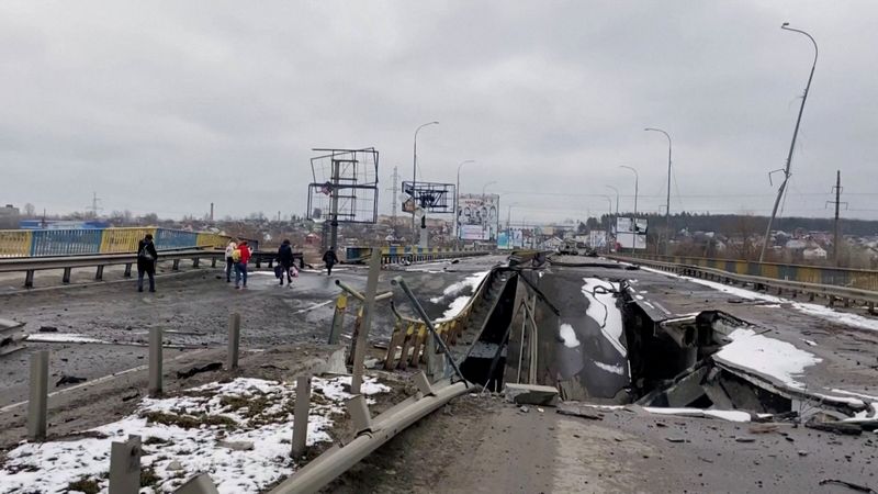 People walk on a partially destroyed bridge, amid Russia’s ongoing