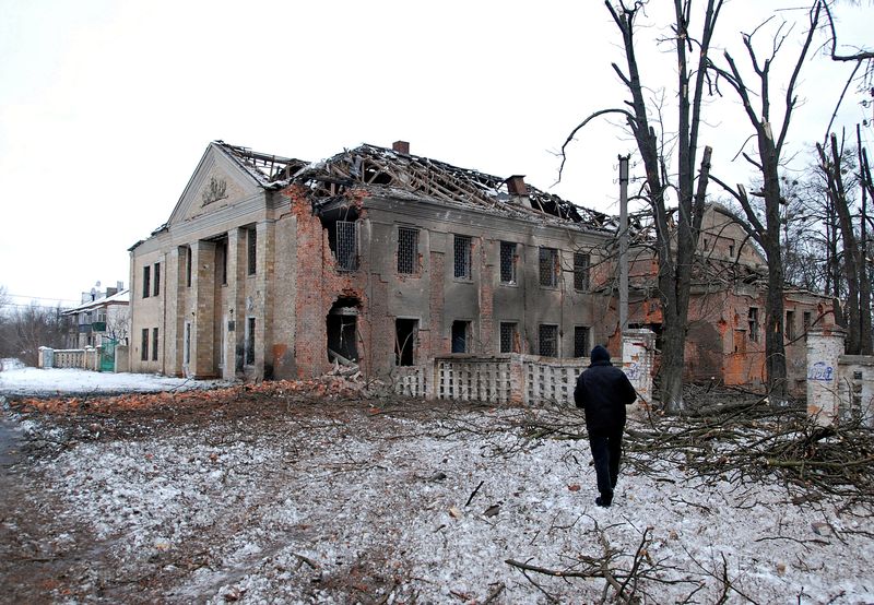 A man walks in front of a building damaged by