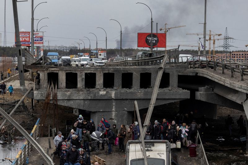Local residents cross a destroyed bridge as they evacuate from