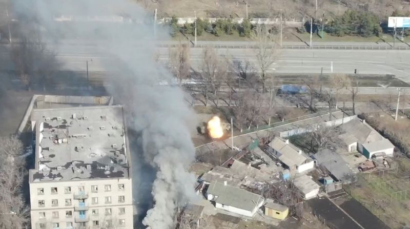 An aeriel view shows smoke rising as an armoured vehicle