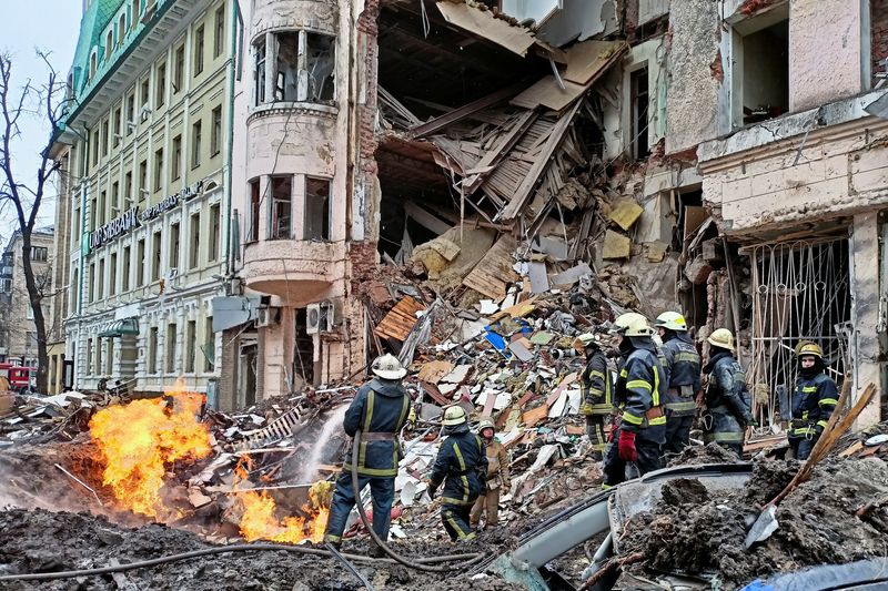 Rescuers work next to a building damaged by air strike