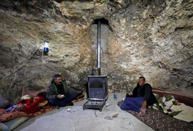 FILE PHOTO: Two Palestinians sit in a hillside cave in