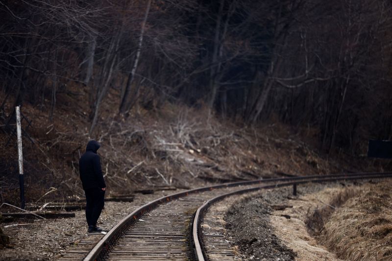 A man walks near railway tracks after crossing the border