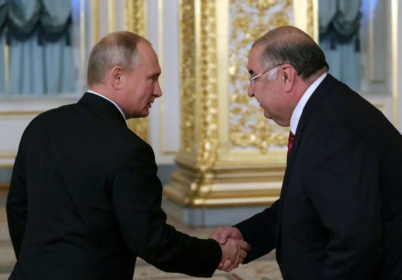 FILE PHOTO: Russian President Putin shakes hands with billionaire Usmanov