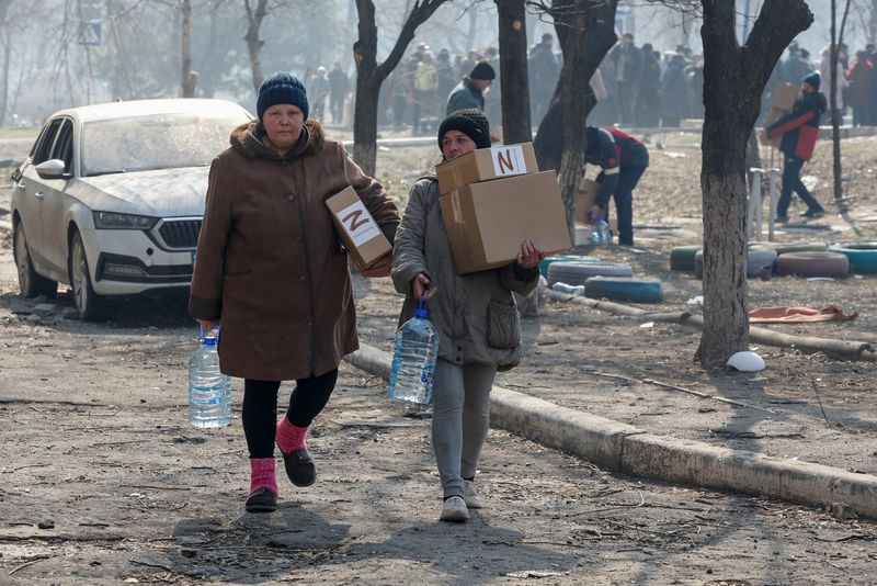 Local residents carry humanitarian aid delivered by Russian soldiers during