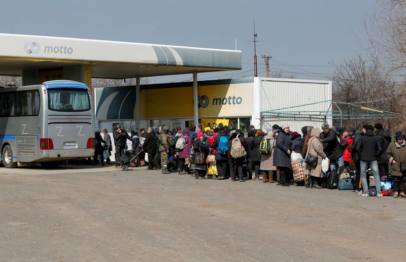 Evacuees wait for a bus before leaving the city of