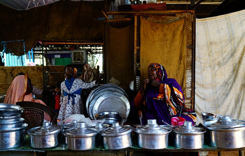 A Sudanese vendor chats with her customers as she sells