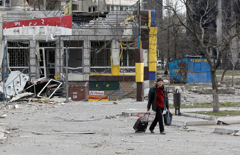 A man walks near a damaged building in Mariupol