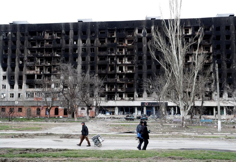 FILE PHOTO: Local residents walk past a burned building in
