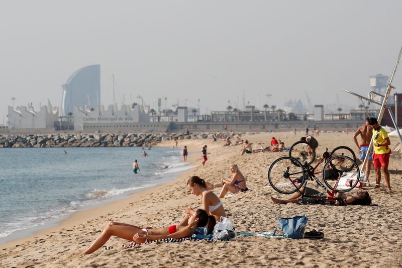 FILE PHOTO: People sunbathe on Barceloneta beach in Barcelona