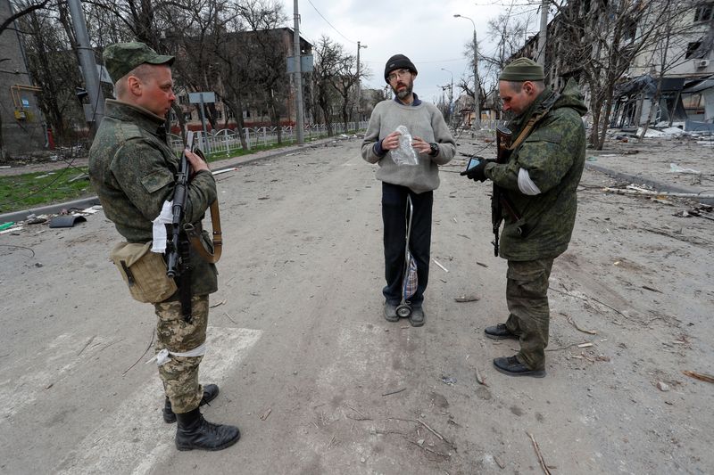 Service members of pro-Russian troops check civilians’ documents in Mariupol