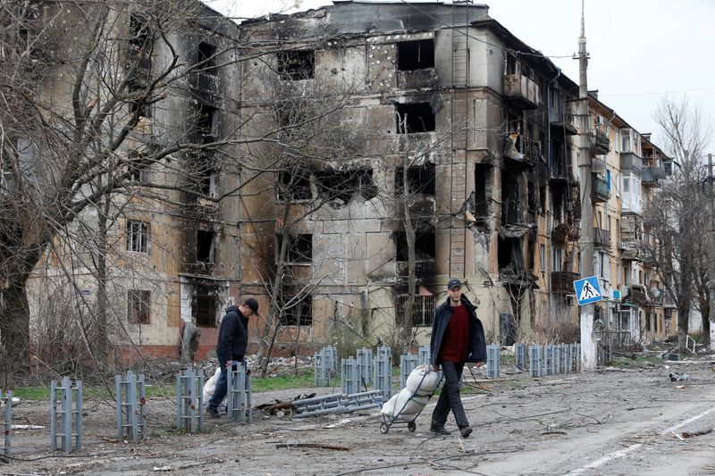 FILE PHOTO: People walk past a damaged residential building in