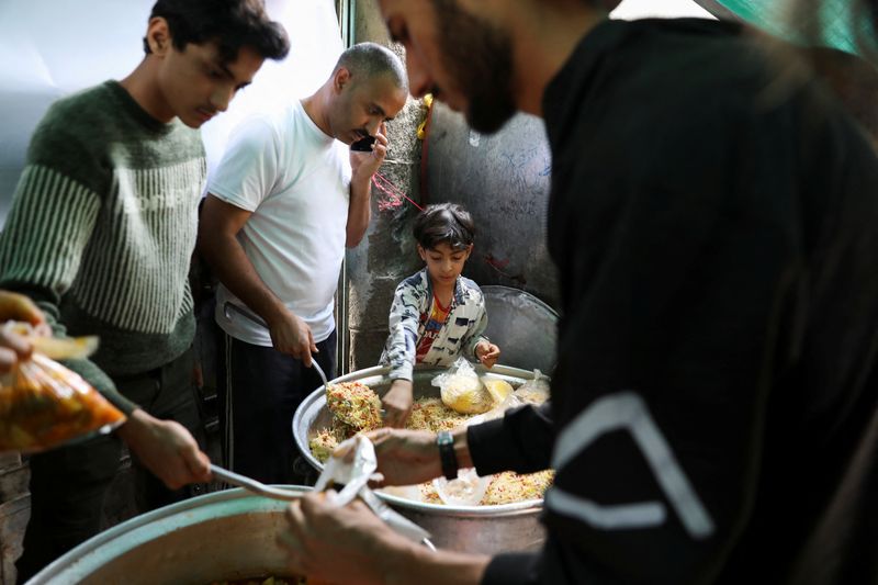 Boy helps volunteers to prepare meals to be distributed at