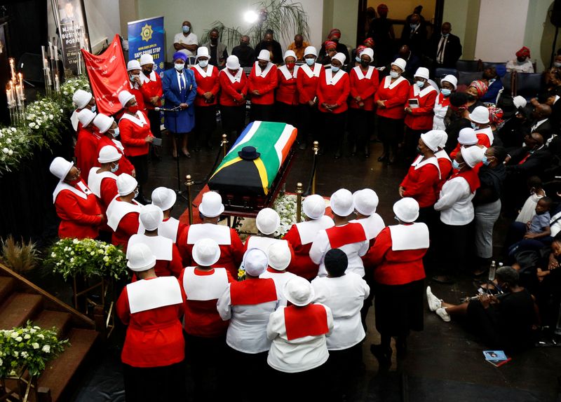 Woman in church uniforms gather around the coffin of police