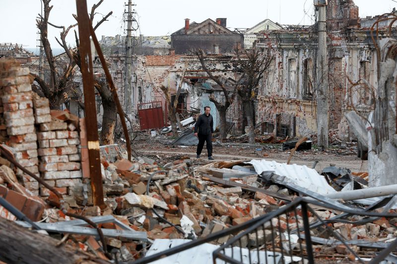 A man walks near damaged buildings in Mariupol