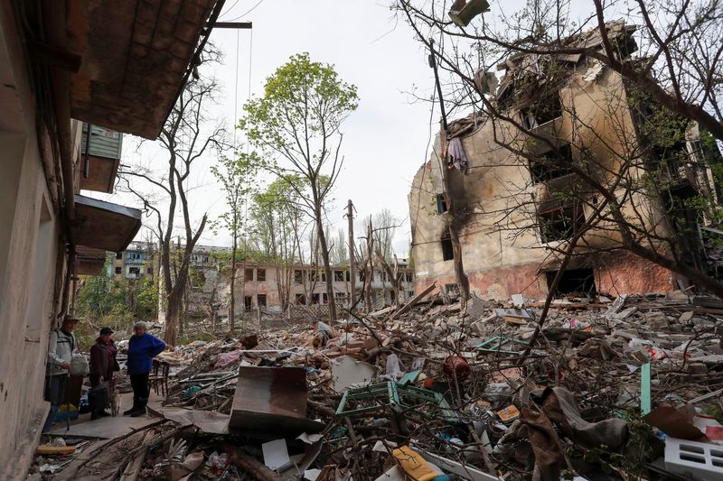 Local residents gather in a courtyard near a damaged building