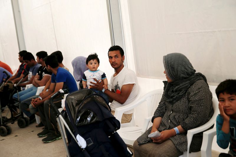 FILE PHOTO: Refugees and migrants wait as they take part