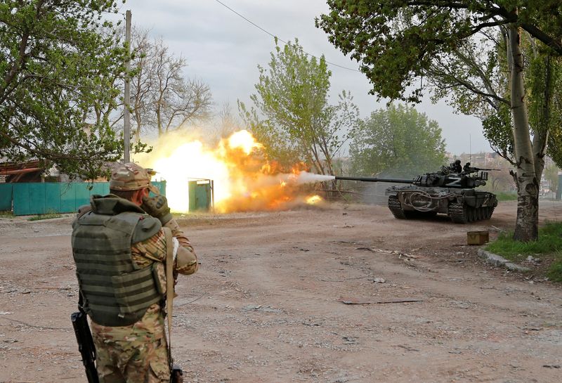 Service members of pro-Russian troops fire from a tank in